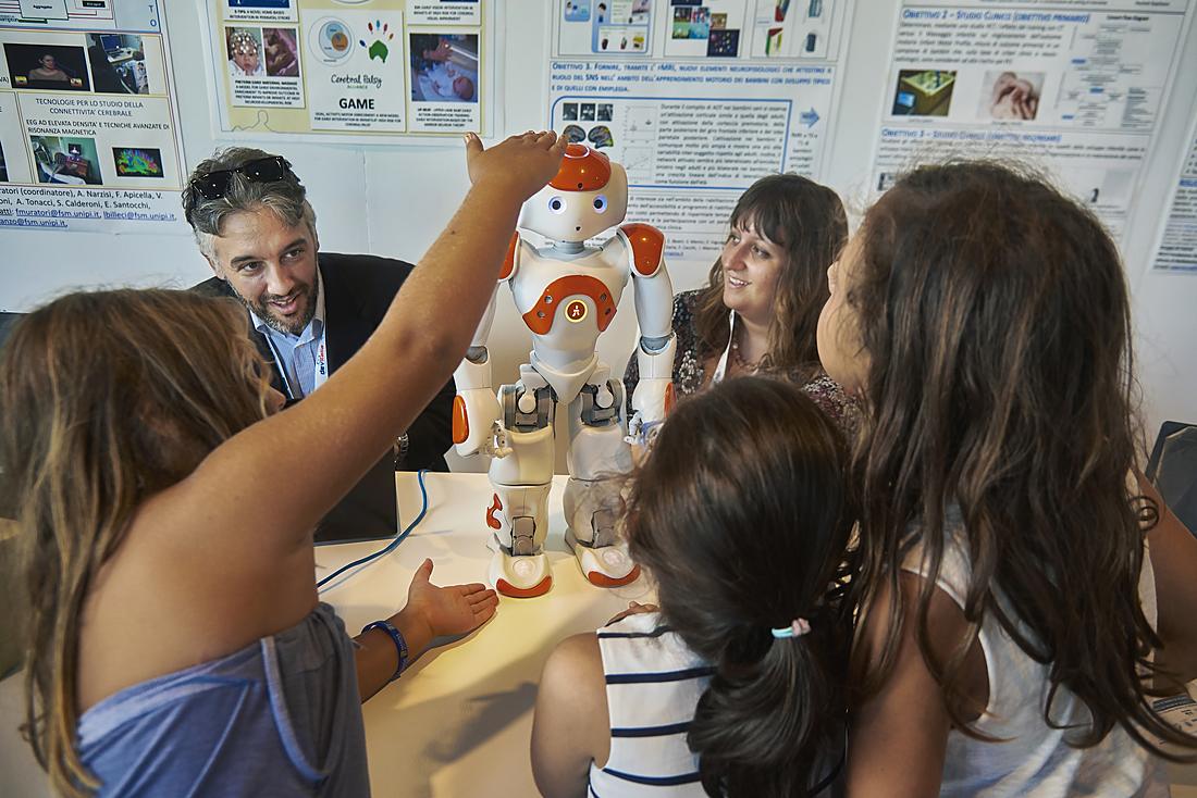 Bambini e un ricercatore interagiscono con il robot umanoide NAO al Festival della Robotica.